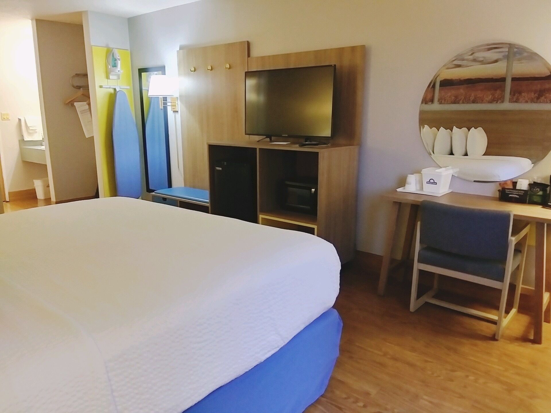 Een hotelkamer met een groot bed, een bureau met stoel, een televisie en een kledingkast.