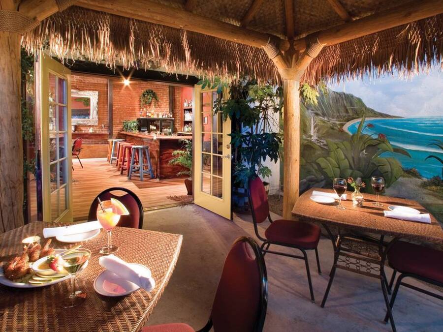 Un espace de restauration en plein air avec vue sur l’océan, un bar et une fresque murale aux motifs tropicaux.