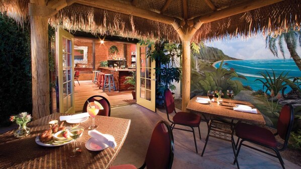 An outdoor dining area with a view of the ocean, a bar, and a tropical mural.