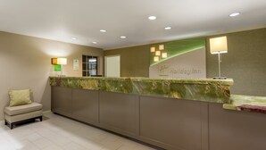 A reception area with a marble counter, a small seating area with a chair and pillow, and a sign reading "Holiday Inn".
