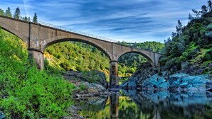 A concrete bridge over a calm river with rocky banks and dense greenery. - Holiday Inn Auburn by IHG (Auburn)