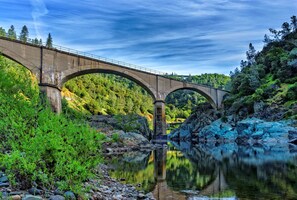 A concrete bridge over a calm river with rocky banks and dense greenery. - Holiday Inn Auburn by IHG (Auburn)