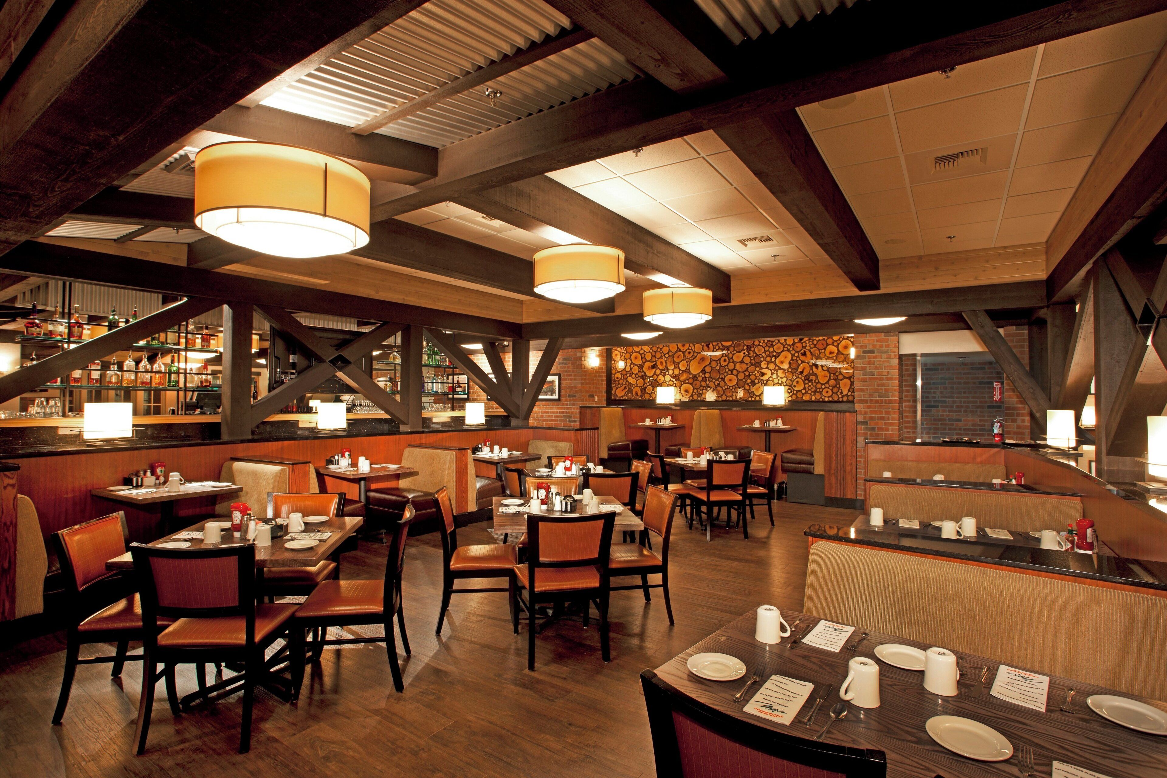 Interior de restaurante con vigas de madera, lámparas colgantes y una zona de bar.