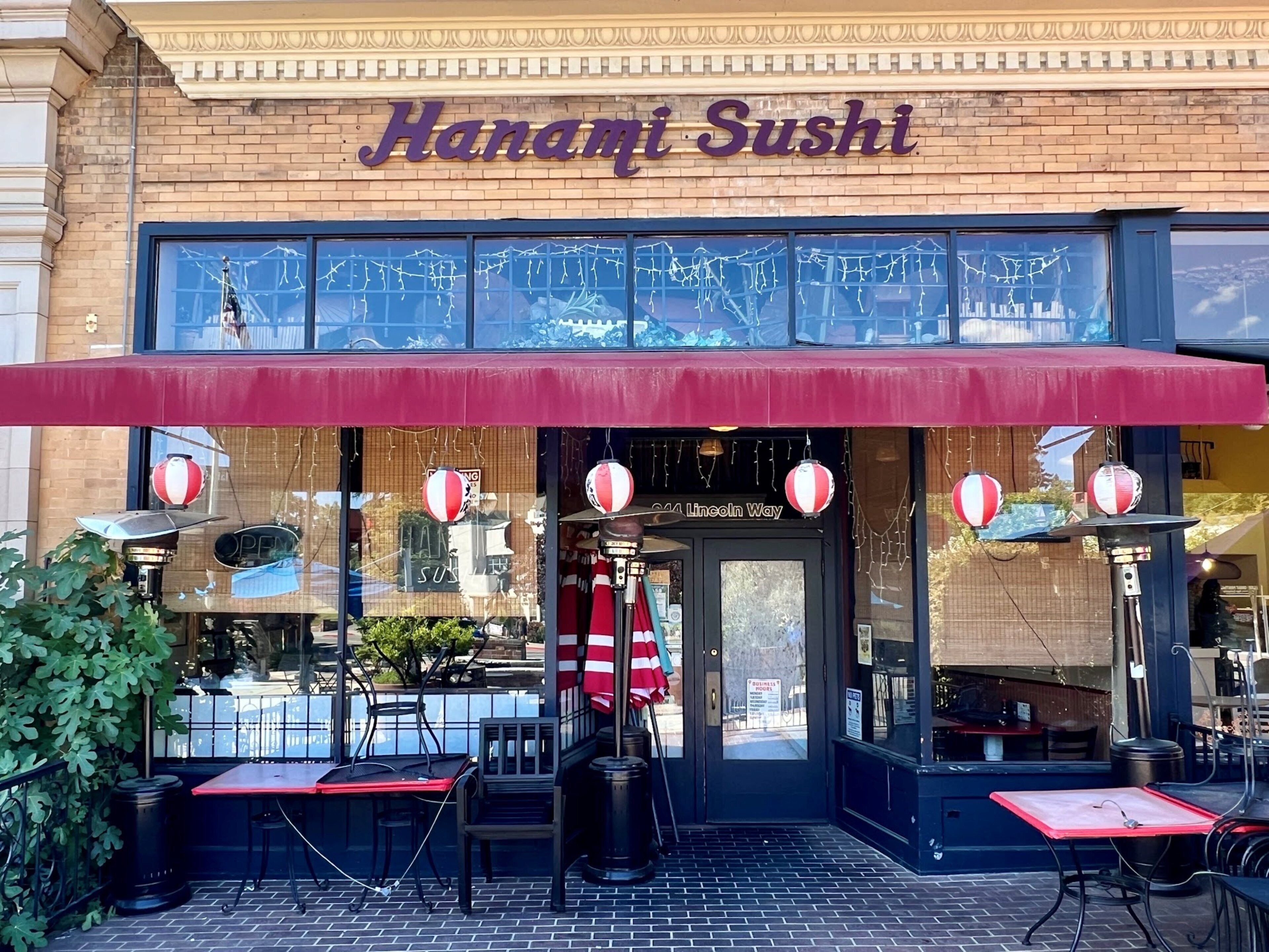 A brick building with a red awning and a sign that reads 'Hanami Sushi.'