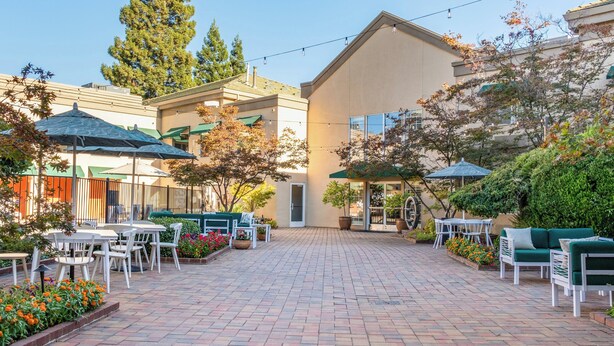 A courtyard with outdoor seating, a building entrance, and surrounding greenery. - Holiday Inn Auburn by IHG (Auburn)