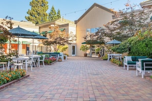 A courtyard with outdoor seating, a building entrance, and surrounding greenery. - Holiday Inn Auburn by IHG (Auburn)