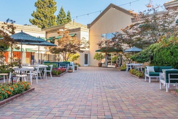 A courtyard with outdoor seating, a building entrance, and surrounding greenery. - Holiday Inn Auburn by IHG (Auburn)