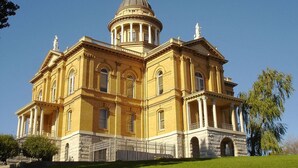 A large, yellow building with a central dome and multiple columns, surrounded by a well-maintained lawn. - Holiday Inn Auburn by IHG (Auburn)