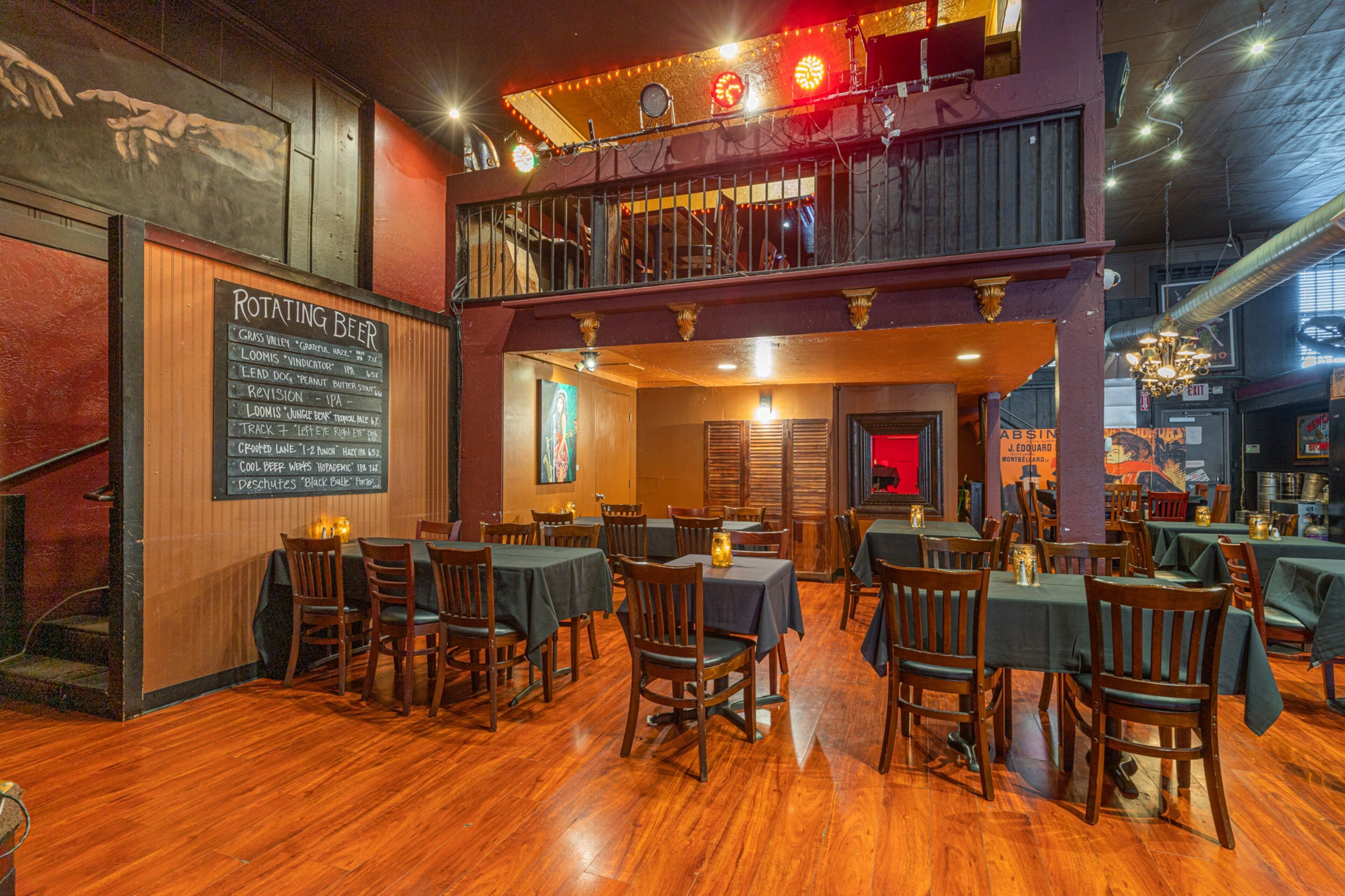 Un restaurante con techo alto, pisos de madera y una pizarra con diferentes cervezas.
