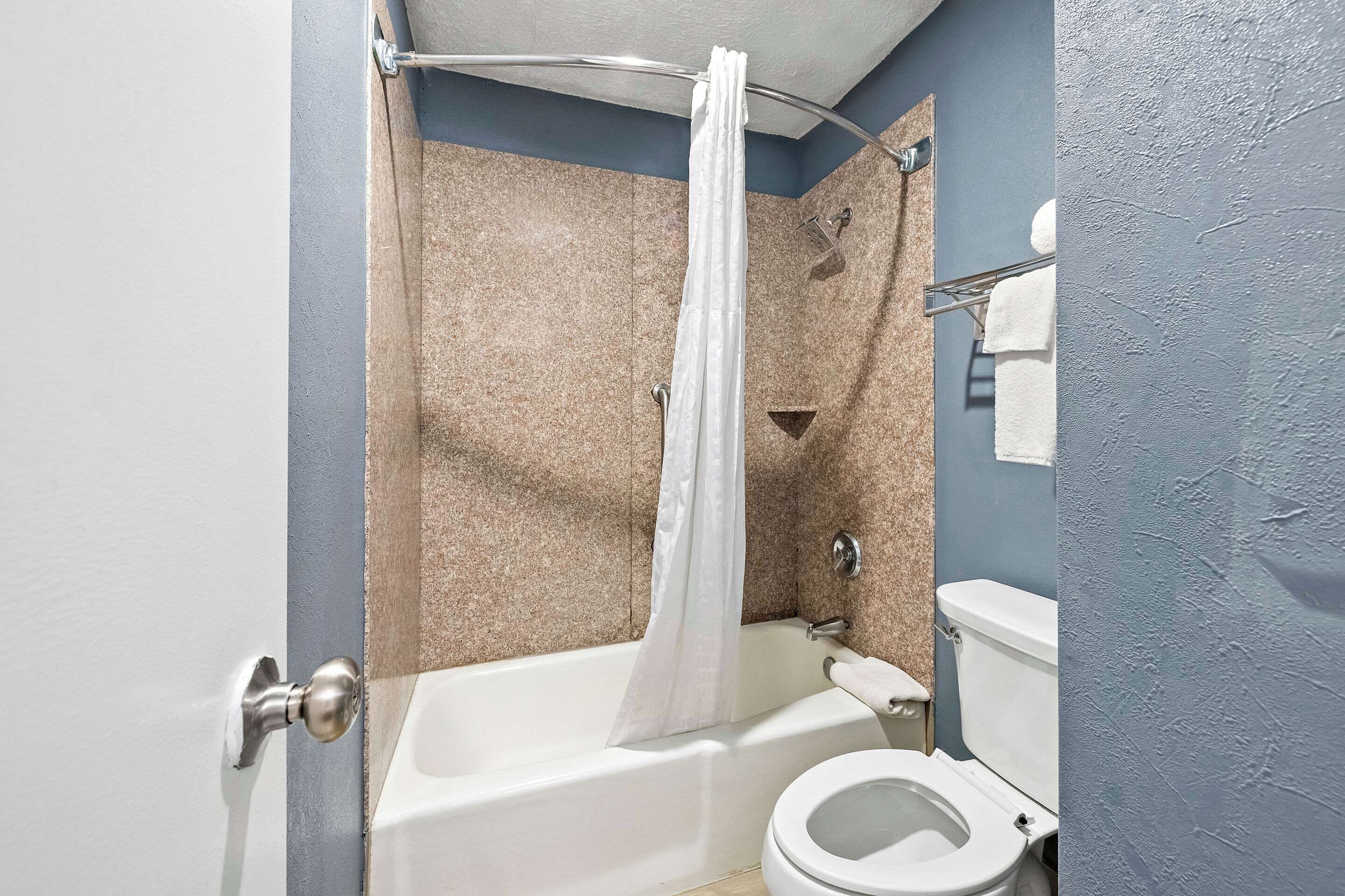 A bathroom with a bathtub, toilet, and shower curtain.