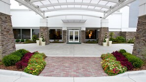 A hotel entrance with a covered walkway, stone pillars, and a brick pathway leading to the doors.