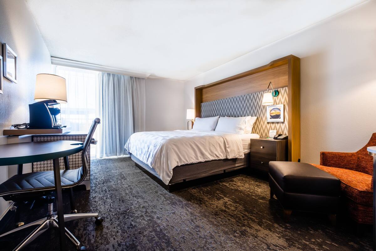 A hotel room with a bed, desk, chair, and a small orange couch.