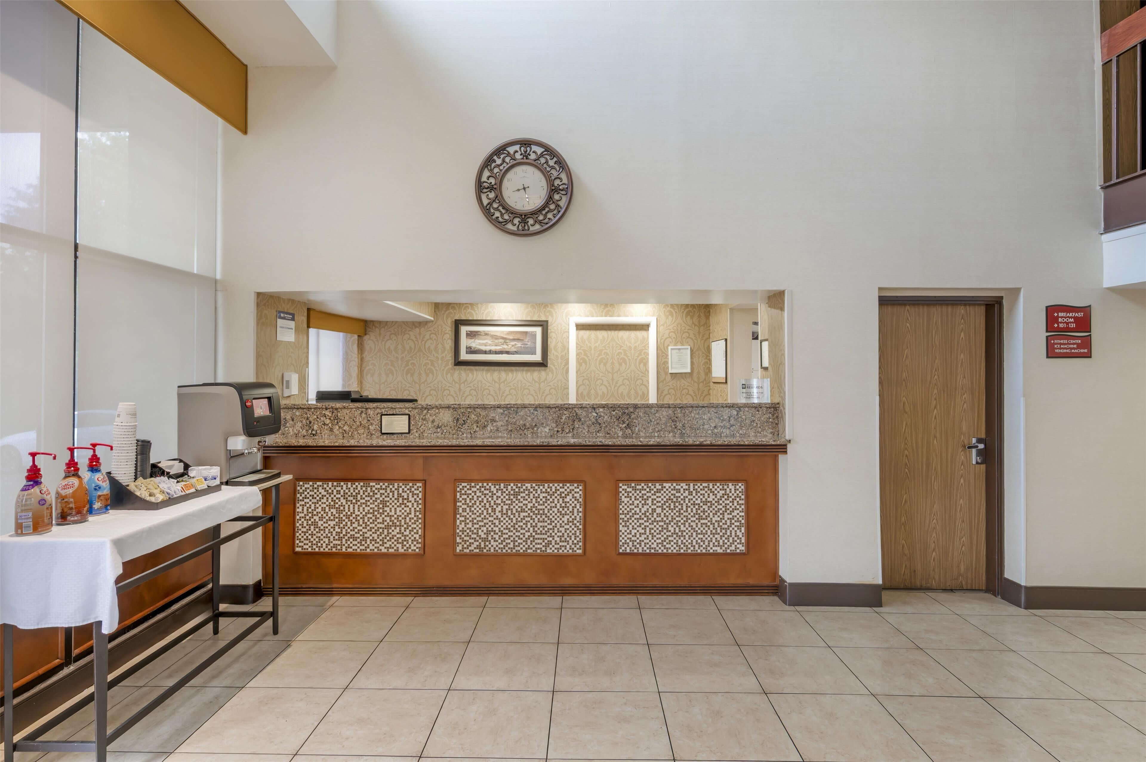 A reception area with a counter, a clock, and a door.