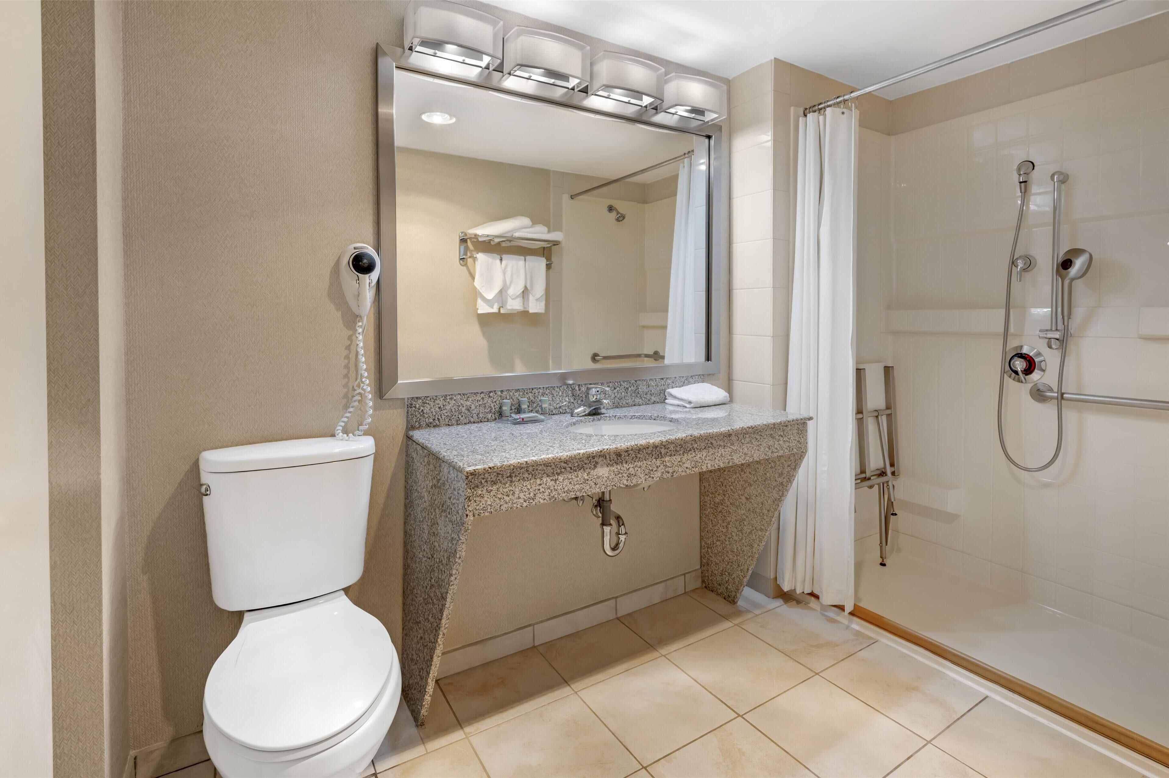 Un baño moderno con inodoro, lavamanos y ducha.
