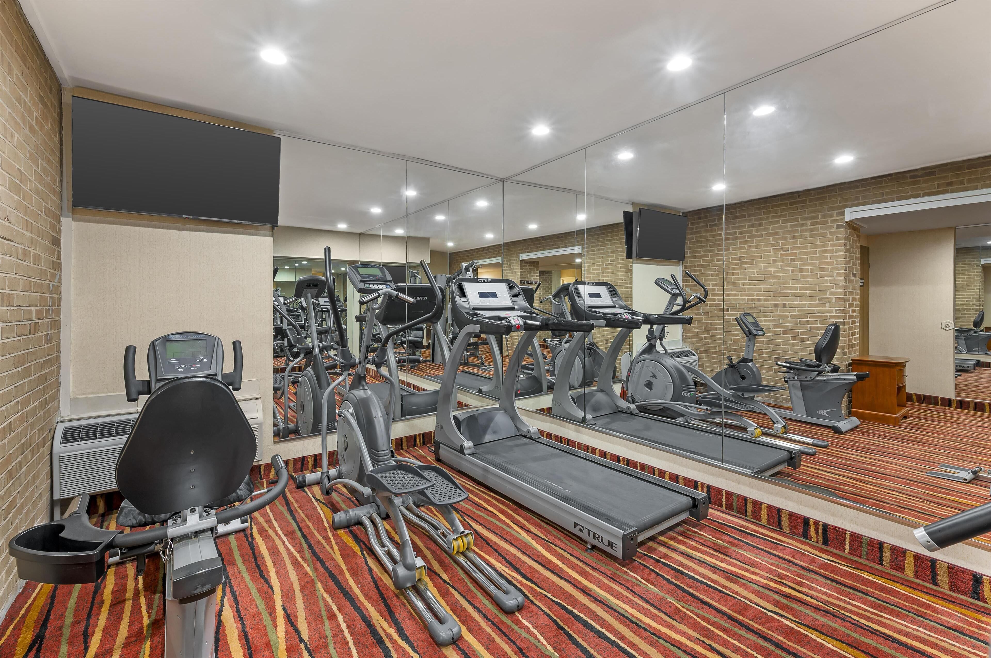 A gym with treadmills, elliptical machines, and a stationary bike.