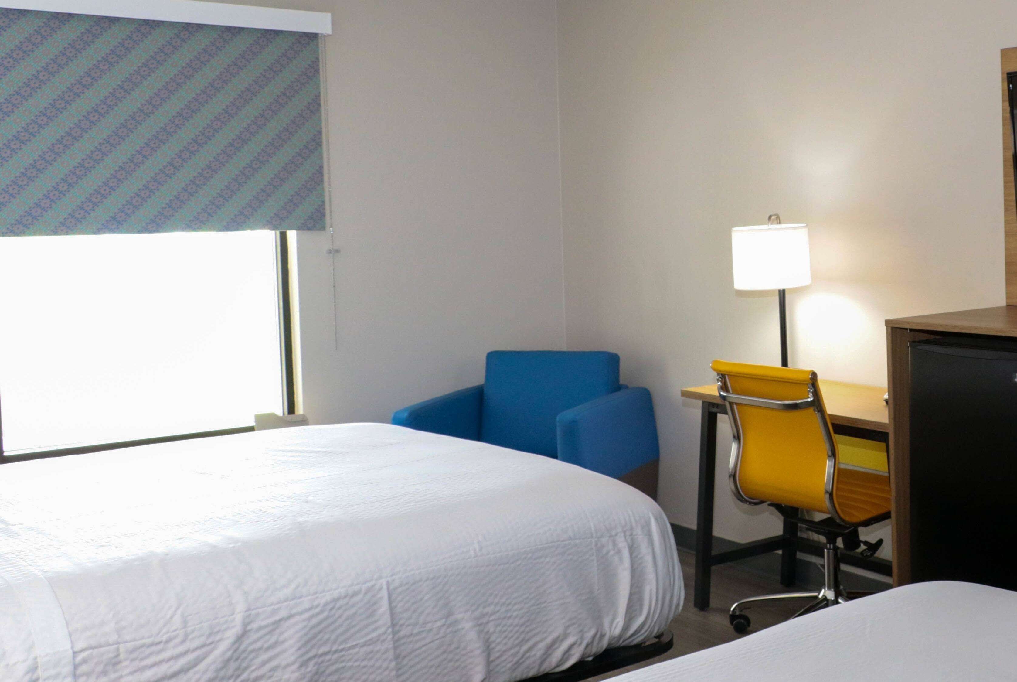 A hotel room with a bed, a desk with a chair, and a lamp.