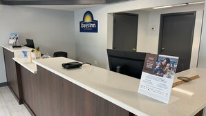 Un comptoir d’accueil dans l’hôtel Days Inn by Wyndham, équipé d’un ordinateur, d’un téléphone et d’une affiche relative au programme de fidélité Wyndham Rewards.