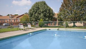 Une piscine avec des chaises longues et une clôture.