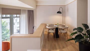 A modern kitchen with a wooden countertop, a round dining table with chairs, a pendant light, and a potted plant.
