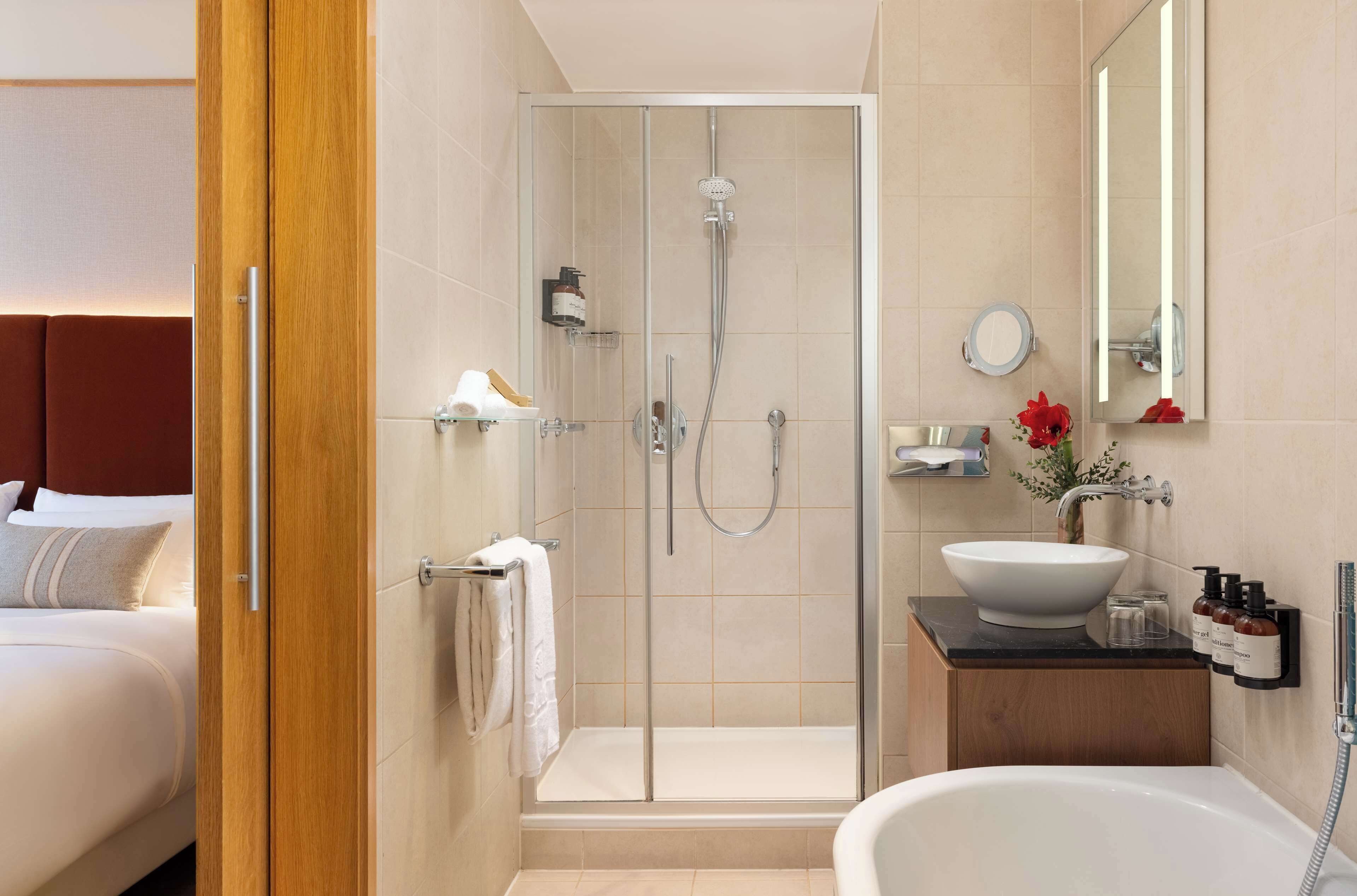 A modern bathroom with a glass-enclosed shower, a freestanding bathtub, and a vanity with a large sink and mirror.