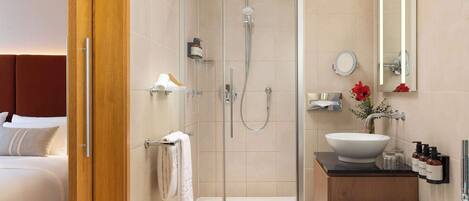 Un baño moderno con ducha envuelta en vidrio, una bañera independiente y un tocador con un lavabo grande y espejo.