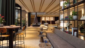 Un hall d’hôtel moderne avec un comptoir d’accueil en bois, des sièges confortables et une bibliothèque agrémentée de livres et de plantes.