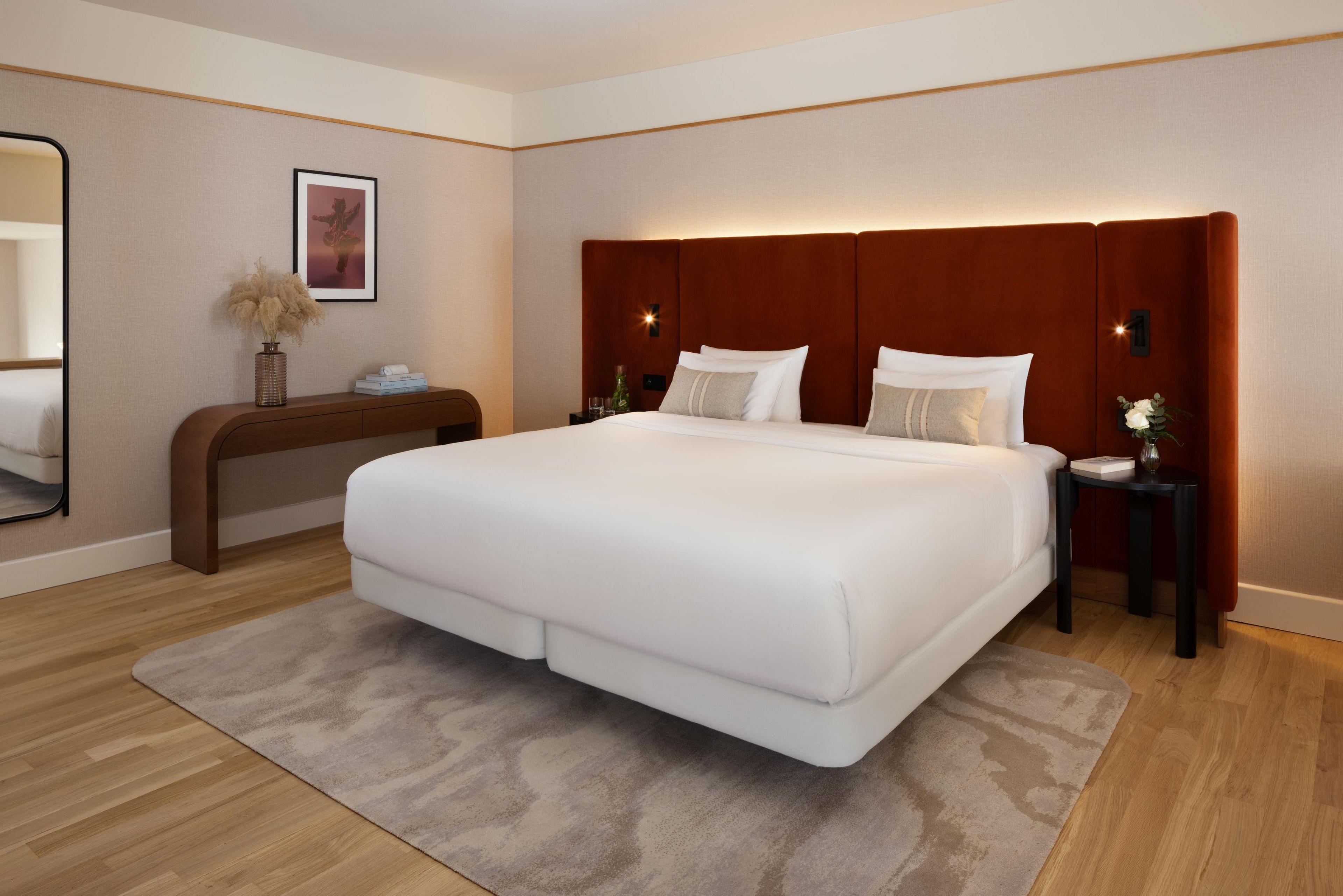 Una camera d'albergo con un letto grande, un comodino, uno specchio e un lampadario a parete.