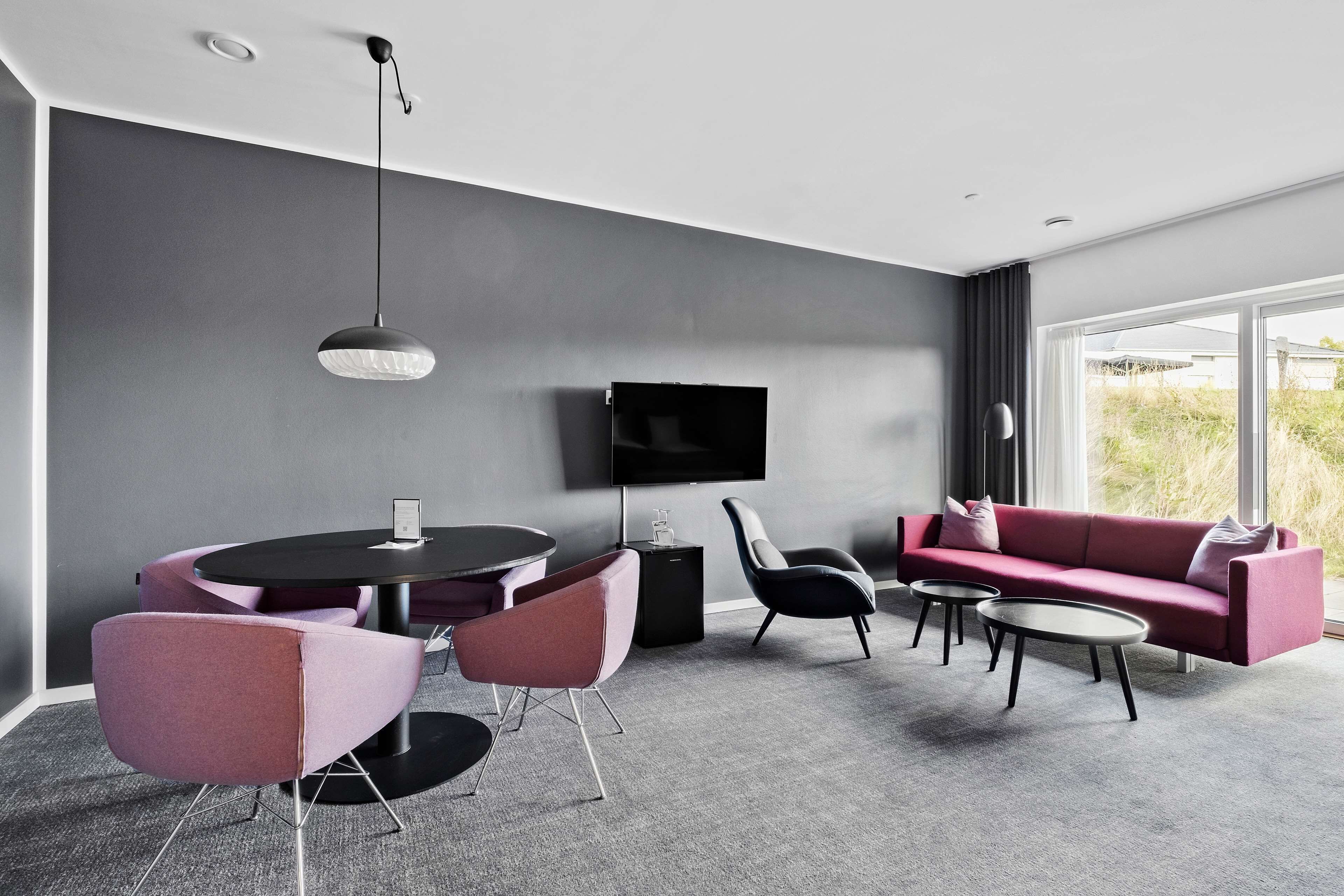 A modern living room with a round table, two sofas, and a flat-screen TV mounted on the wall.