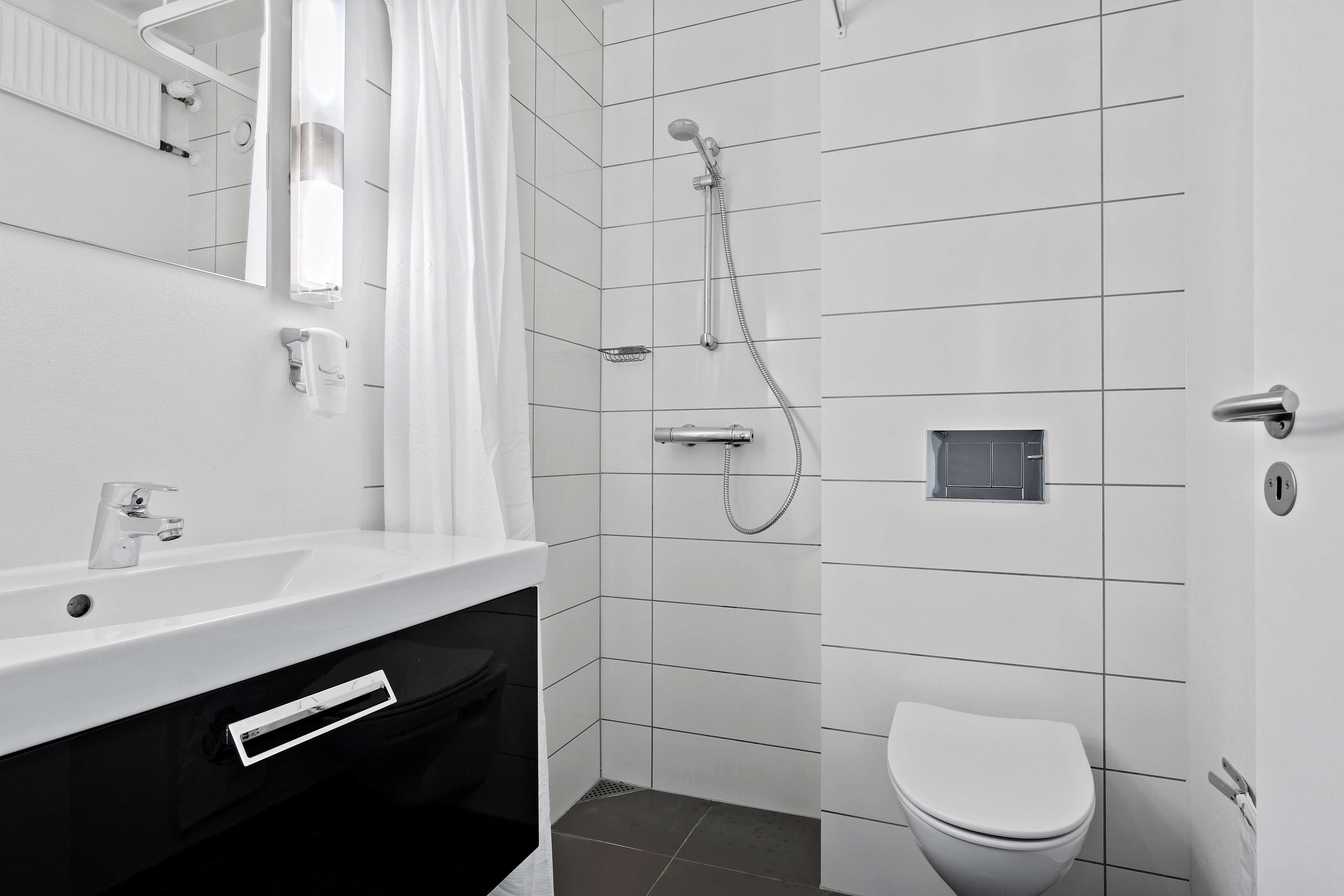 A modern bathroom with a white sink, mirror, and toilet.