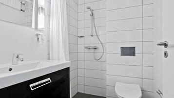 A modern bathroom with a white sink, mirror, and toilet.