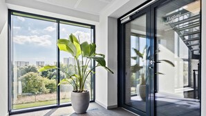 Un interior moderno con ventanas amplias, una planta en maceta y vista a la ciudad.