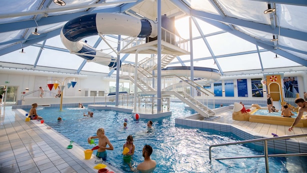Una piscina interior con toboganes y tragaluces.