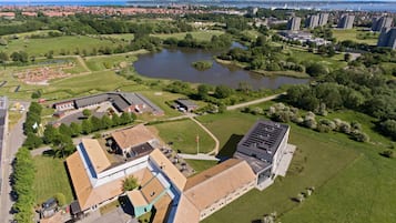 An aerial view of a campus with buildings, green spaces, and a lake.