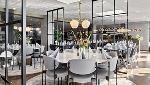 Un comedor moderno con mesas redondas, sillas grises y una lámpara central.