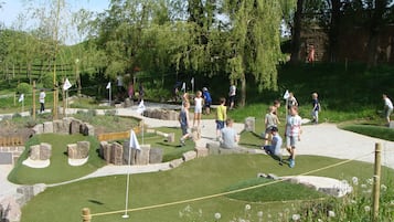 Un parcours de mini-golf avec un chemin sinueux, de l’herbe verte et divers obstacles.