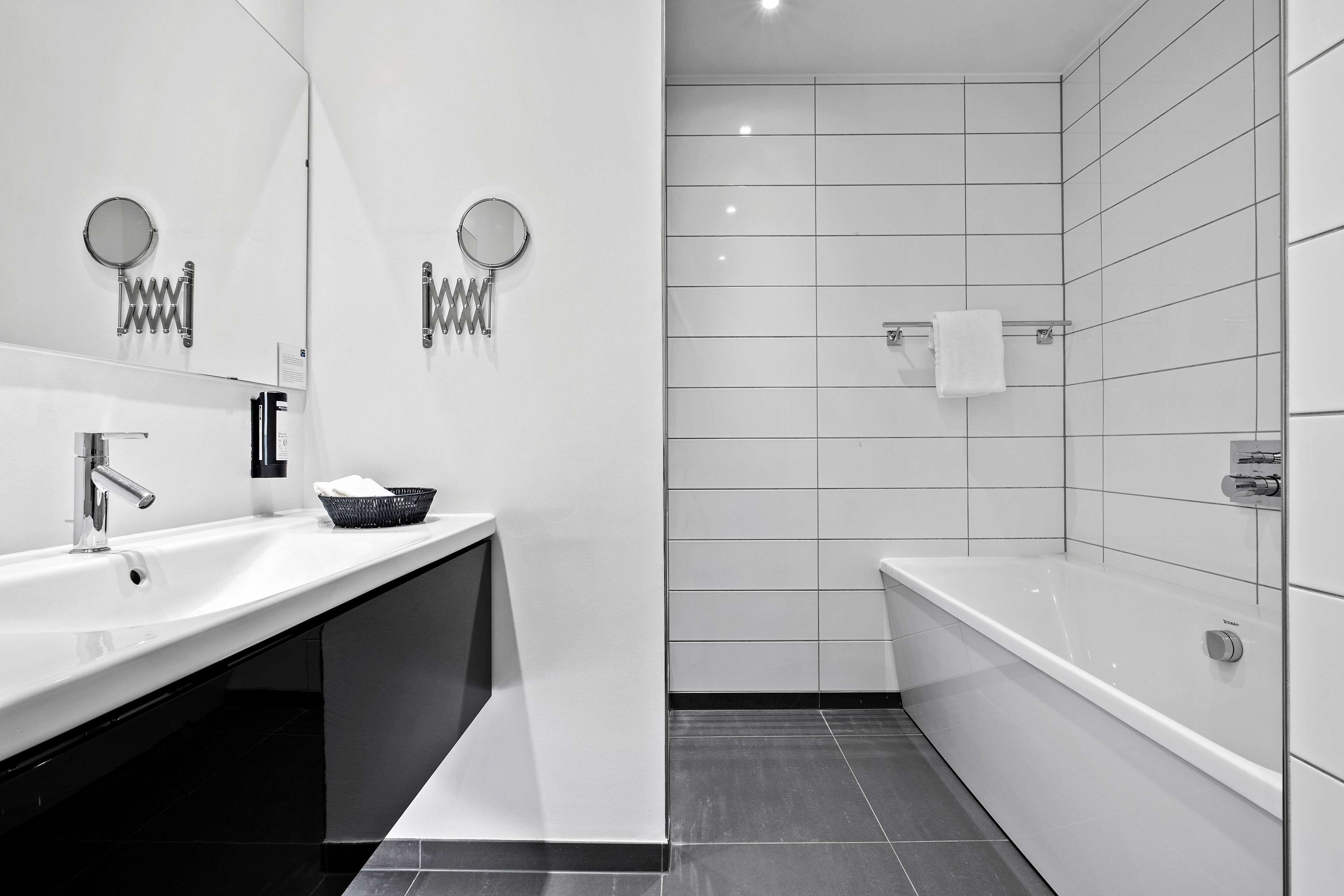 A modern bathroom with a white sink, a mirror, and a bathtub.
