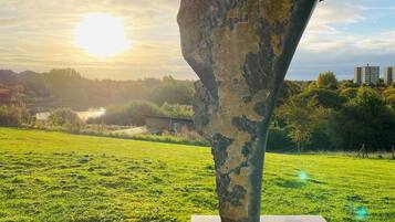 Una scultura in un prato erboso con un tramonto sullo sfondo.