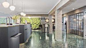 Un vestíbulo moderno con mostrador de recepción, zona de estar y una pared verde.