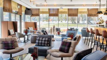 A modern interior with seating areas, a bar, and large windows offering a view of the outdoors.