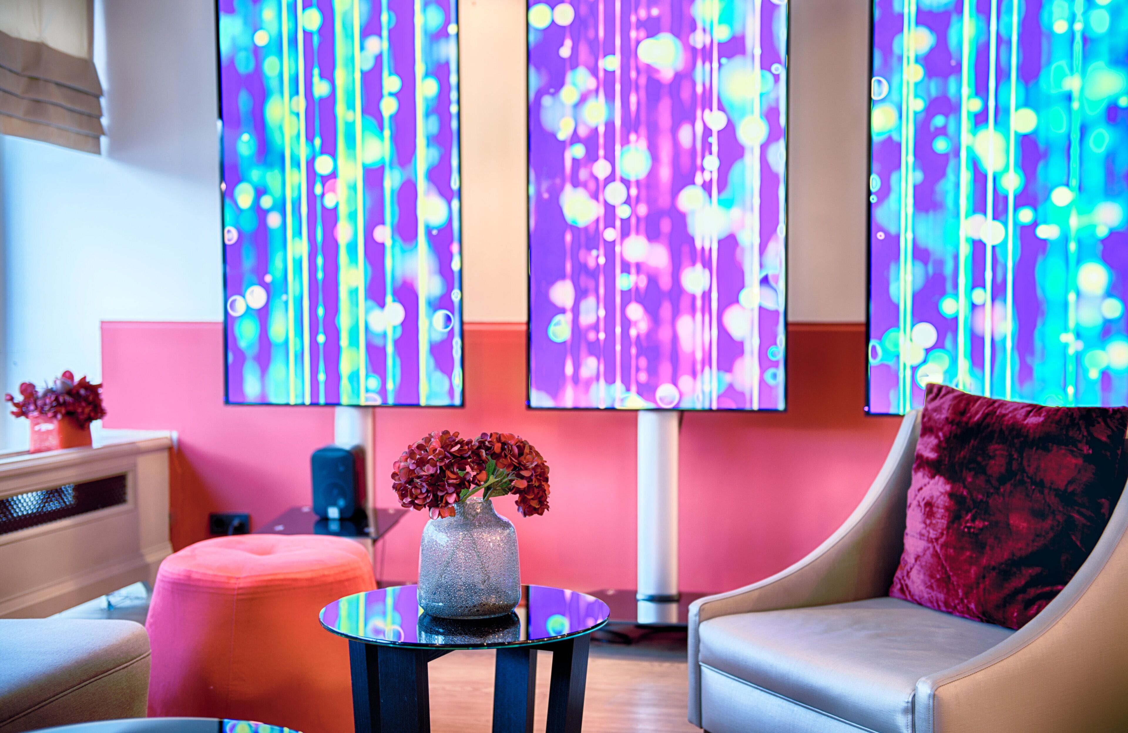 Un interior moderno con un sofá, un reposapiés y una mesa con un jarrón de flores.