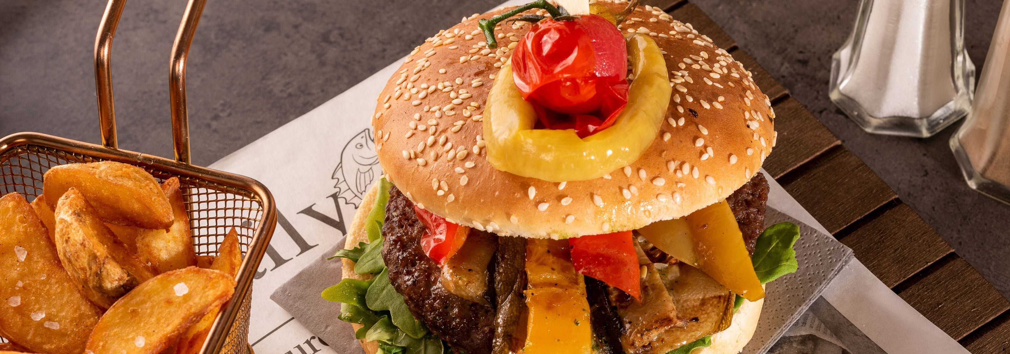A burger with various toppings and a side of fries on a table.