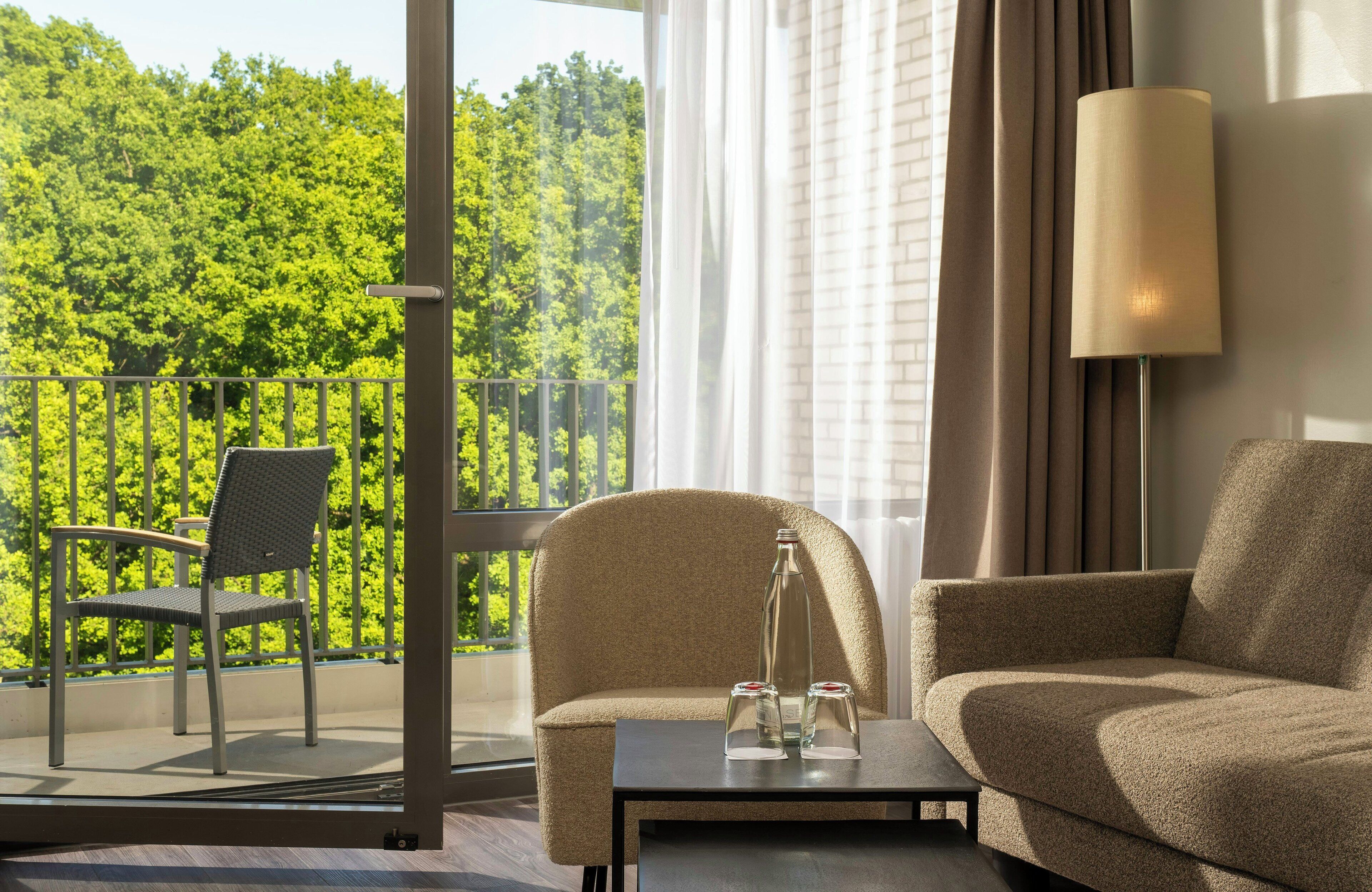 A balcony with a chair and a table, a sofa, and a lamp.