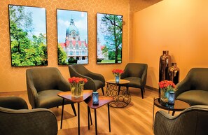Relax in a stylish lounge area with plush sofas, armchairs, and a coffee table, surrounded by scenic photographs and decorative vases.