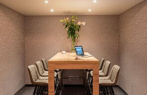 Meetings take place in this well-appointed conference room, equipped with a large table and comfortable seating for six.