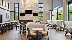 A modern dining area with a stone wall, large windows, and contemporary furniture. - Wyndham Atlanta Buckhead Hotel & Conference Center (Atlanta)