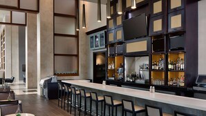 A modern bar area with a long counter, multiple bar stools, and a variety of bottles and glasses on shelves. - Wyndham Atlanta Buckhead Hotel & Conference Center (Atlanta)
