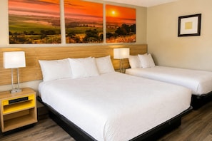 A hotel room with two beds, a wooden headboard, bedside lamps, a small yellow nightstand, and a framed picture on the wall. - Days Inn by Wyndham KU Lawrence (Lawrence)