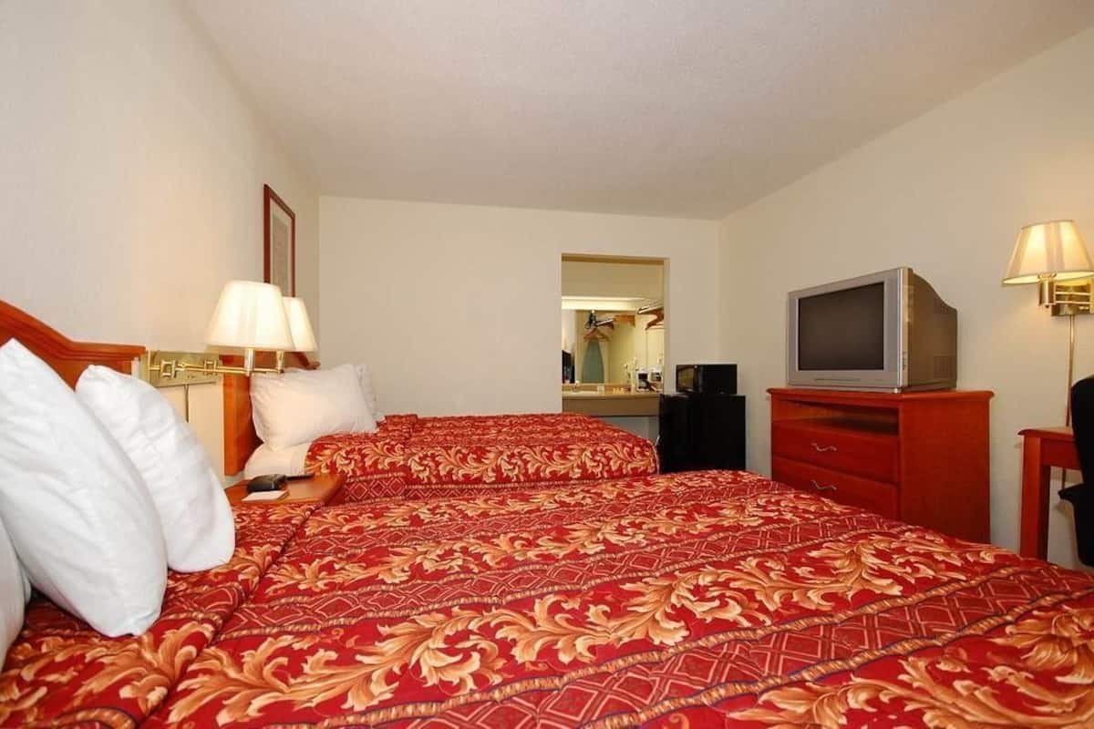 Une chambre d’hôtel avec un grand lit, une télévision, un bureau et un miroir.