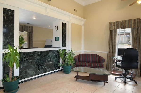A reception area with a marble counter, potted plants, a striped sofa, a glass coffee table, and a black office chair. - Days Inn by Wyndham KU Lawrence (Lawrence)