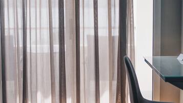 Una habitación de hotel con cama, una silla y cortinas translúcidas.
